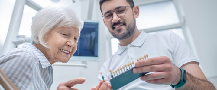 An older lady taking a look at a span of dental implants with a dentist showing her the crowns and bridges available