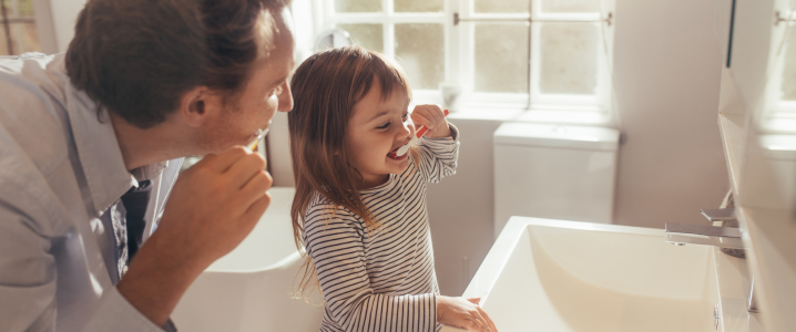 Father showing daughter tooth brushing techniques 